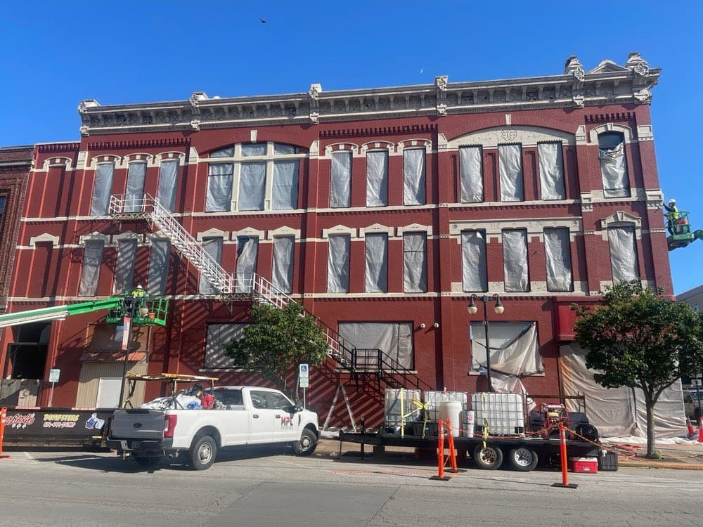 Commercial building painting in progress with equipment and crew