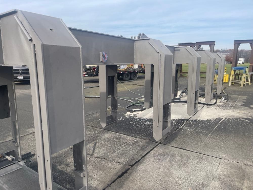 Multiple large steel frames lined up after sandblasting