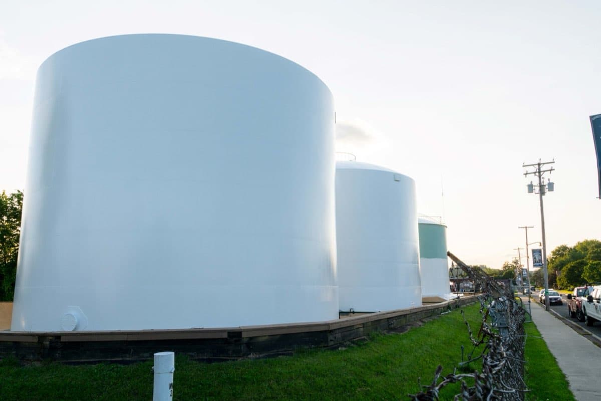 Row of large white fuel storage tanks painted by MPC