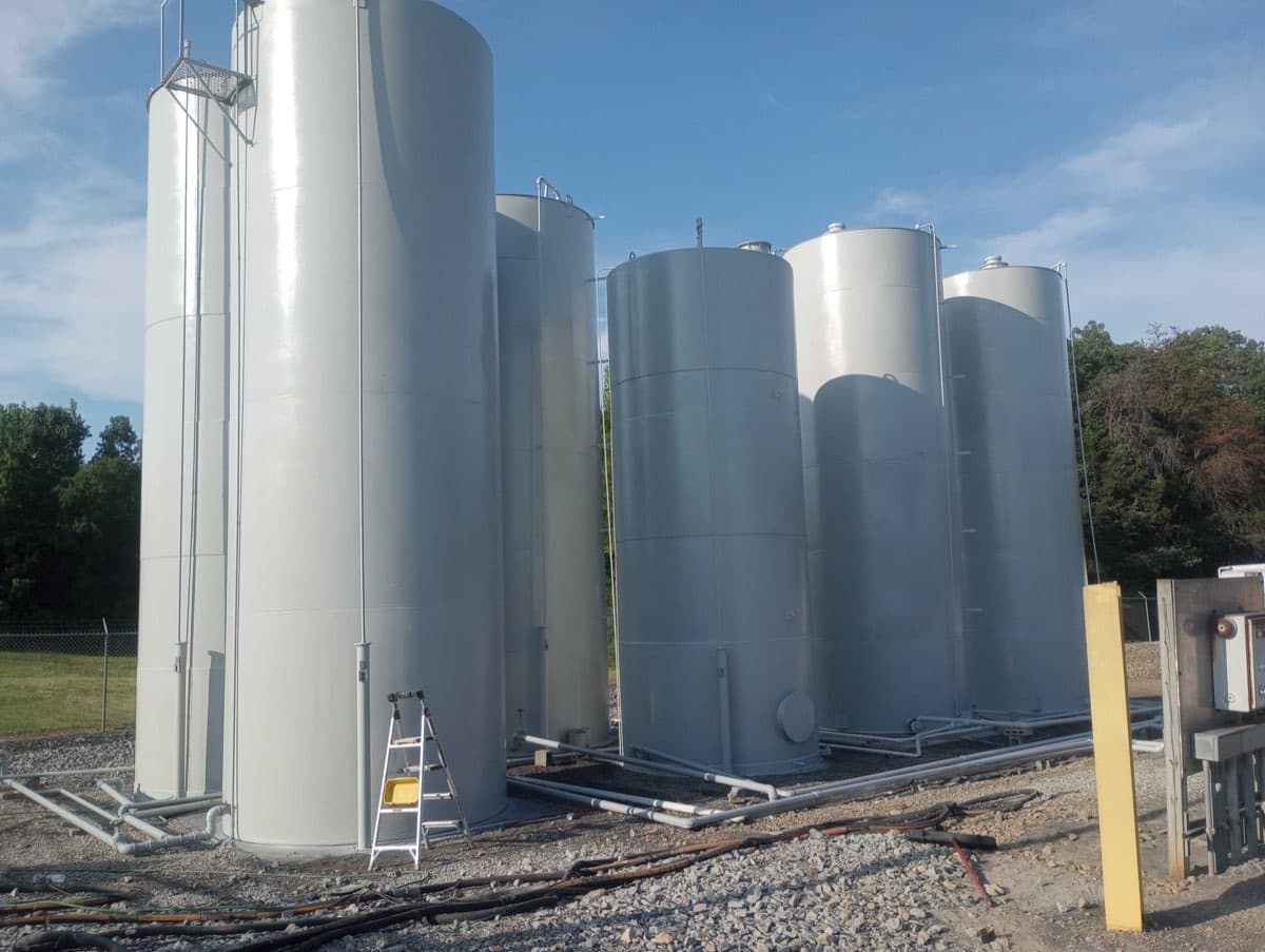 Multiple tall oil storage tanks professionally painted by Markley's Precision