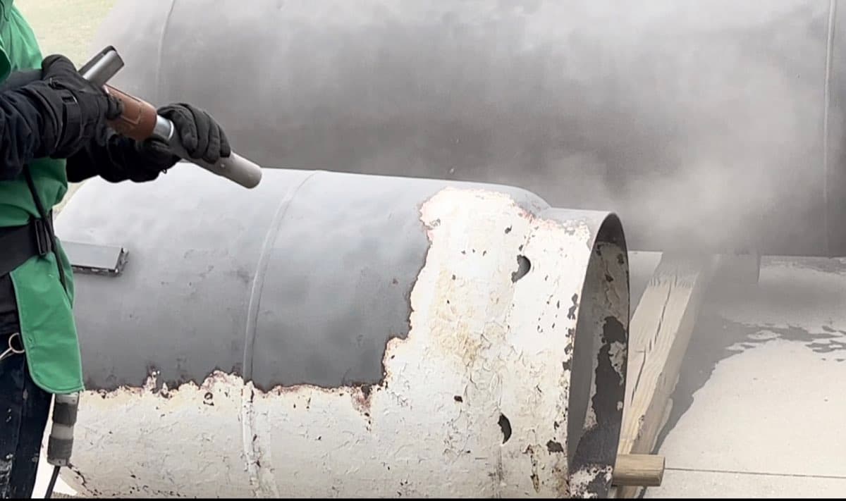 MPC worker sandblasting a propane tank — surface prep in action