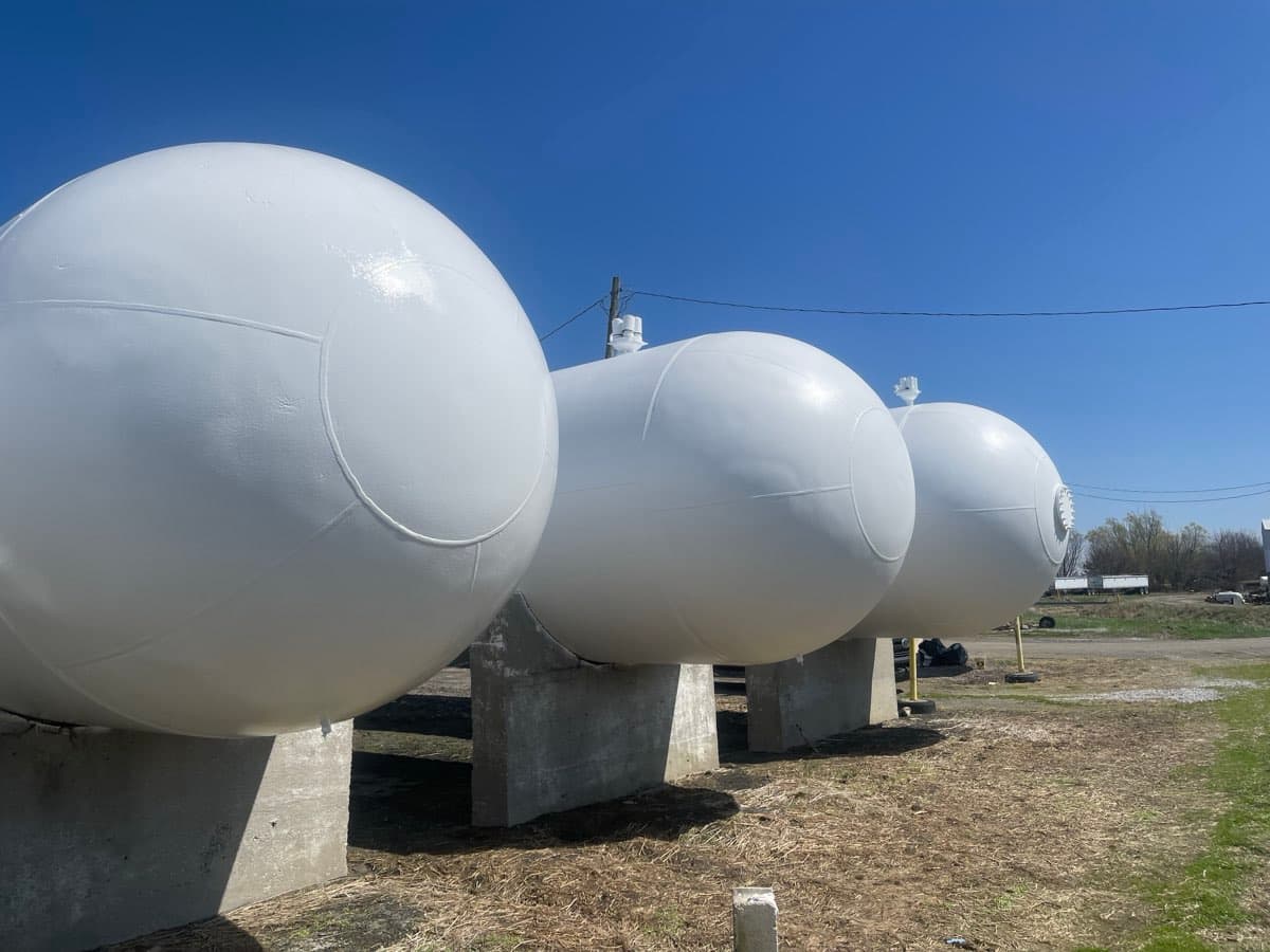 Row of large spherical propane tanks freshly painted white